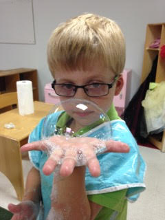 A kid from Sunshine Nursery School’s summer camp having fun making giant bubbles.